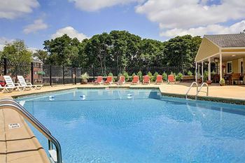 a large pool with chairs around it and trees in the background